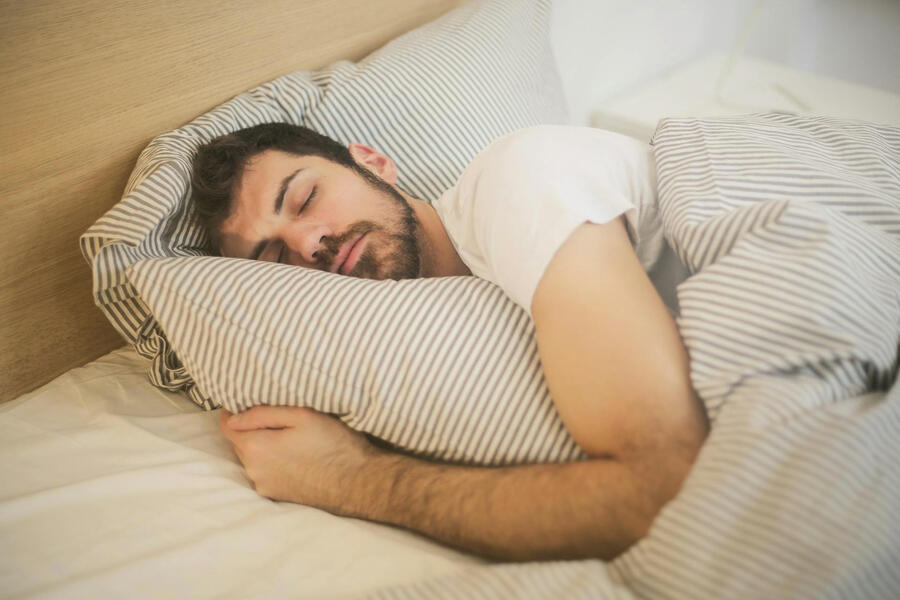 a man is sleeping in bed, hugging the pillow