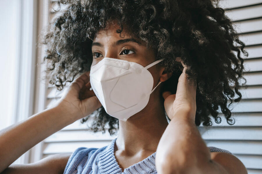 A black woman dons a respirator